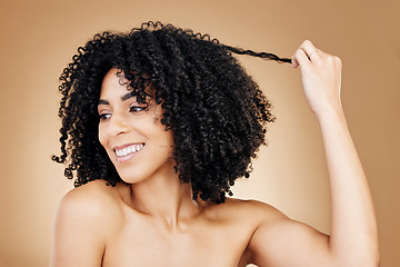 Image showing Curly, hair and strand of woman in studio for natural beauty, healthy growth and coil textures on brown background. Model, smile and pull afro hairstyle for salon aesthetic, keratin treatment or care
