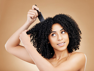 Image showing Hair care, afro and woman with a comb, beauty and treatment on a brown background. Person, girl and model with salon grooming, volume or shine with glow, wellness and aesthetic with texture and clean