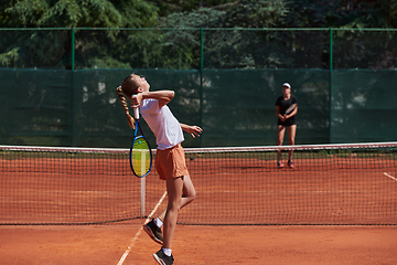 Image showing Young girls in a lively tennis match on a sunny day, demonstrating their skills and enthusiasm on a modern tennis court.