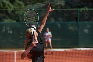 Image showing Young girls in a lively tennis match on a sunny day, demonstrating their skills and enthusiasm on a modern tennis court.