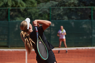 Image showing Young girls in a lively tennis match on a sunny day, demonstrating their skills and enthusiasm on a modern tennis court.