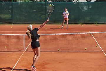 Image showing Young girls in a lively tennis match on a sunny day, demonstrating their skills and enthusiasm on a modern tennis court.