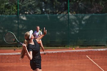 Image showing Young girls in a lively tennis match on a sunny day, demonstrating their skills and enthusiasm on a modern tennis court.