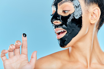 Image showing Skincare, charcoal mask and finger of woman for facial treatment, anti aging detox and wellness. Beauty, studio and person with face products for health, cosmetics or grooming on blue background