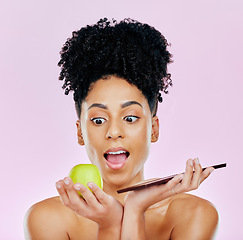 Image showing Woman in studio with apple, chocolate and choice for food, wellness and skincare nutrition. Fruit vs sweets, diet and decision for beauty model on pink background with challenge for healthy eating.