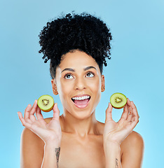 Image showing Kiwi, skincare and excited woman in studio for cosmetic wellness or results on blue background. Happy, face and female with fruit for beauty, pamper or glowing skin routine with detox, shine or glow