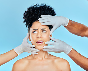 Image showing Skincare, plastic surgery and fear, woman with hands on face in studio for cosmetic consultation. Model with stress, worry and anxiety for beauty, dermatology or collagen therapy on blue background.