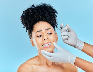 Image showing Filler, fear and woman with hands on face in studio for collagen skincare injection or implant. Model with stress, anxiety and syringe for beauty, dermatology or cosmetic process on blue background.