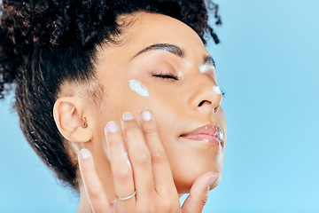 Image showing Beauty, face and relax woman with cream application of ointment, lotion or collagen for skin hydration, wellness or spa skincare. Eyes closed, anti aging routine and studio model on blue background