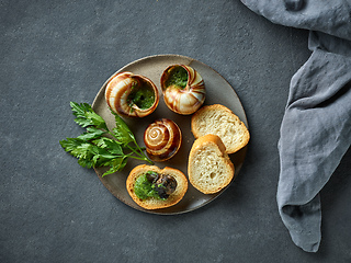 Image showing plate of baked escargot snails filled with parsley and garlic bu