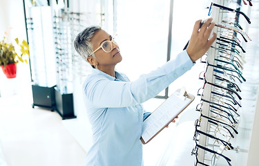 Image showing Stock, optometrist or senior woman with glasses checklist in store for retail inventory or eyewear choice. Vision, product or optician in clinic writing on clipboard for eye care in optometry shop