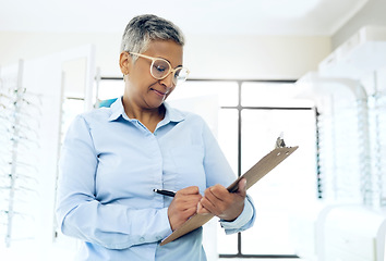 Image showing Writing, optometrist or mature manager with glasses checklist for store inventory or eyewear choice. Woman, product info or optician in clinic with clipboard for eye care notes in optometry shop