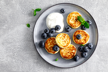 Image showing Cottage cheese fritters with fresh blueberry and yogurt for breakfast, copy space, view from above