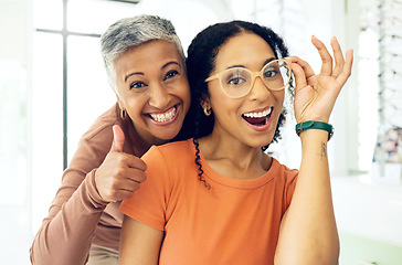 Image showing Optometry, thumbs up or happy woman with glasses for vision in a retail optical or eyewear shop. Women, smile or biracial customer with new spectacles with a mature optometrist at optics clinic store