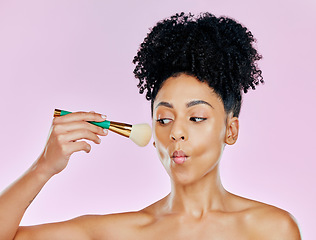 Image showing Beauty, makeup and a woman on a pink background in studio for facial cosmetology or skincare. Face, cosmetics and blush with a confident young model using a brush to apply foundation to her skin