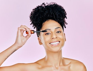 Image showing Portrait, smile and mascara with a woman on a pink background in studio to apply makeup or cosmetics. Beauty, skincare and face product with a happy young model on color for eyelash cosmetology