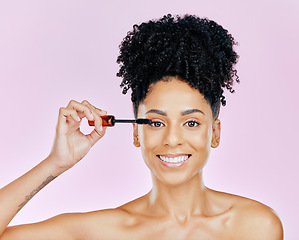 Image showing Portrait, beauty and mascara with a woman on a pink background in studio to apply makeup or cosmetics. Smile, skincare and face product with a happy young model on color for eyelash cosmetology