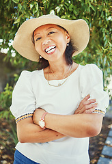 Image showing Mature woman, portrait and arms crossed in garden with sun hat for summer, vacation and outdoor with smile, Japanese person, happy and spring in backyard, park and nature for walk on path in Tokyo