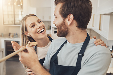 Image showing Cooking, taste and happy couple in kitchen bonding while preparing a meal in their home together. Food, spoon and man feeding woman in a house with romance, smile and having fun on weekend or day off