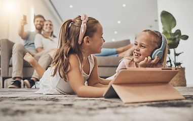 Image showing Happy kids on floor of living room with tablet, headphones and watching video, movie streaming or music. Digital game, online app and girl children relax on carpet together with fun in family home.
