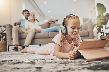 Image showing Child, headphones and tablet on floor in home education, listening to audio and streaming with parents in living room. Happy girl kid with digital e learning, video games and school or family holiday