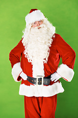 Image showing Santa claus, hands and hips in studio portrait for Christmas holiday, festive season or warning. Male person, costume suit and arm gesture on green background for vacation, celebration or gift giving