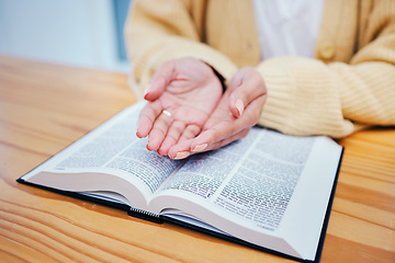 Image showing Hands, bible and prayer at desk, religion and Christian worship in home at table. Closeup, holy book and woman in meditation for God, Jesus and Christ for faith in spiritual gospel, praise or hope