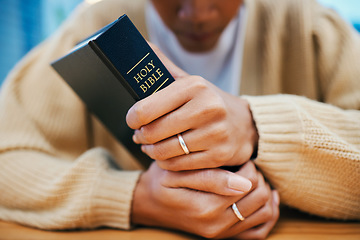 Image showing Hands, bible and prayer at desk, religion and Christian worship in home at table. Closeup, holy book and woman in meditation for God, Jesus and Christ for faith in spiritual gospel, praise or hope