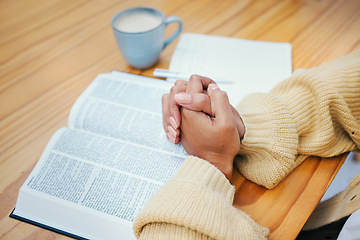 Image showing Hands, bible and praying at table, religion and Christian worship in home at desk. Closeup, holy book and woman in meditation for God, Jesus and Christ for faith in spiritual gospel, praise or hope