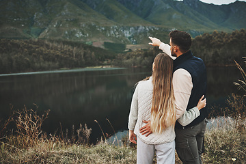 Image showing Couple, relax and pointing to mountain for hiking, camping or nature for outdoor scenery together. Rear view of man and woman hug enjoying holiday vacation, travel trip or trekking adventure outside