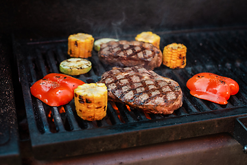 Image showing Beef steaks on the grill with flames