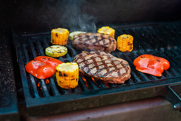 Image showing Beef steaks on the grill with flames