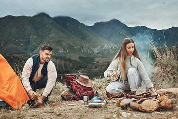 Image showing Couple, camping and pitch tent in nature for vacation, holiday and travel together. Campfire, man and woman outdoor in preparation for adventure, hiking and trekking in the countryside for freedom