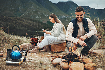 Image showing Wood, nature and couple with fire on a camp on a mountain for adventure, weekend trip or vacation. Stone, sticks and young man and woman making a flame or spark in outdoor woods or forest for holiday