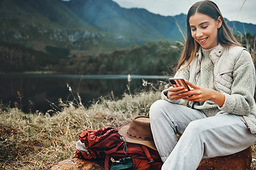 Image showing Nature, smile and woman on a phone for hiking on a mountain and network on social media or mobile app. Happy, technology and young female person scroll on internet with cellphone in outdoor forest.