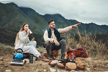 Image showing Couple, mountain and pointing in relax for camping, nature or outdoor scenery together by camp fire. Happy man and woman enjoying natural view, hiking or holiday vacation outside on trip or adventure