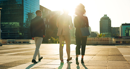 Image showing Back, business team and walking outdoor in city for morning travel to work, conversation and lens flare. Rear View, professional workers and moving in urban town with communication and networking