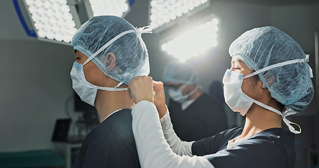 Image showing Surgery, hospital and doctors tie mask in operating room for medical service, preparation and operation. Healthcare team, safety scrubs and people with uniform for emergency, procedure and protection