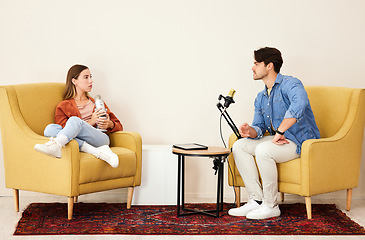 Image showing Man, woman and mic for podcast, speaking or question in conversation, interview and lounge chair. Talk show, microphone and people together for broadcast, live streaming and tablet for social network