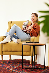 Image showing Microphone, smile and woman hosting a podcast on a chair by a wall in her modern home. Radio, broadcast and happy young female person hosting a journalism talk show in a recording space at her house.