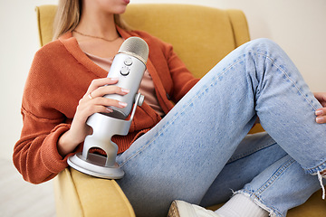 Image showing Microphone, closeup and woman hosting a podcast on a chair by a wall in her modern home. Radio, broadcast and young female person hosting a journalism talk show in a recording space at her house.