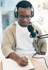 Image showing Radio, podcast and black man in office writing notes for advice, questions or feedback while live streaming. Speech, presenter and African male with broadcast announcement, news or hosting talk show