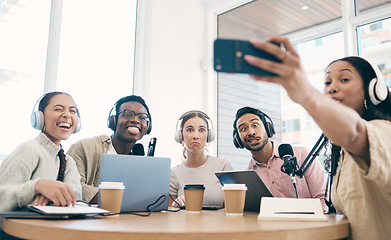 Image showing Podcast, funny face and group selfie of friends together, live streaming or people recording broadcast on headphones or mic in studio. Radio host team laughing, take photo at table and social media