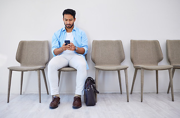 Image showing Waiting room, phone and man in an office for interview in job search for appointment. Hiring, career and Indian male person sitting for recruitment meeting with human resources in modern workplace.