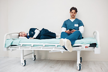 Image showing Tired doctors, woman and man in hallway with phone, texting and relax on bed at hospital job. Medic team, partnership or friends with burnout, smartphone and fatigue with healthcare, clinic and rest