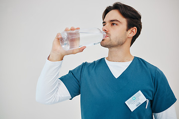 Image showing Surgeon, man drinking water in bottle and health, wellness or body nutrition in studio isolated on white background in hospital. Medical professional, hydration and liquid of thirsty nurse on break