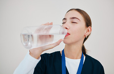 Image showing Nurse, woman drinking water in bottle for health, wellness or body nutrition isolated on white background in hospital. Medical professional, hydration and mineral liquid of thirsty surgeon on a break