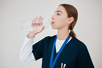 Image showing Nurse, woman drinking water in bottle and health, wellness or body nutrition in studio isolated on white background in hospital. Medical professional, hydration and liquid of thirsty surgeon on break