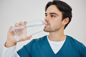 Image showing Nurse, man drinking water in bottle and health, wellness or body nutrition in studio isolated on a white background in hospital. Medical professional, hydration and liquid of thirsty surgeon on break