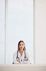 Image showing Portrait, doctor and medical with a woman arms crossed in a hospital for healthcare, consulting or trust. Space, serious and a confident young medicine professional at a desk in a cardiology clinic